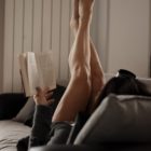 Donna con gambe sollevate sul divano a fine giornata, sensazione di gambe pesanti e gonfie nonostante l’allenamento
